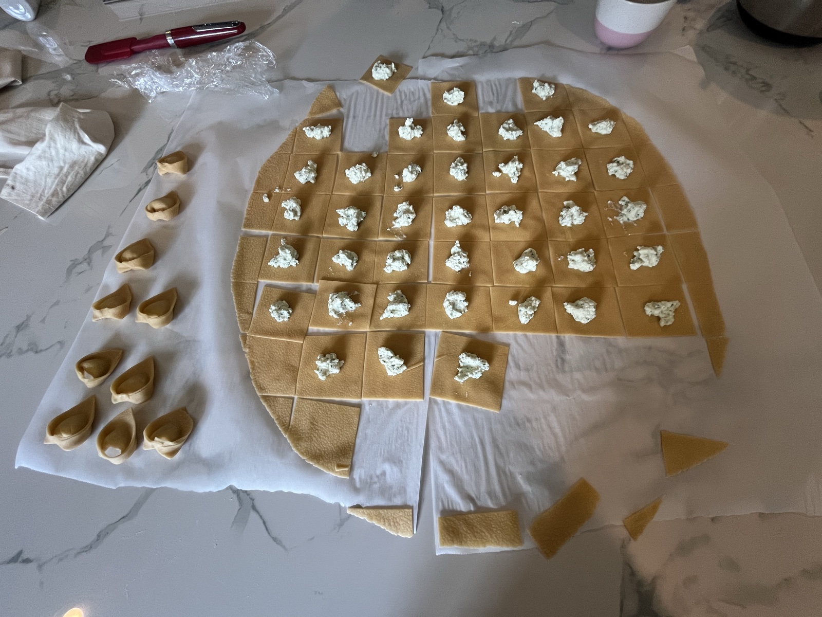Ricotta filling being placed on squares of pasta dough.