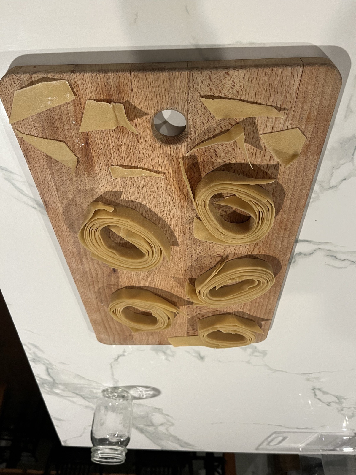 Hand-rolled tagliatelle nests on a wooden board.